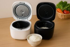 木目調のカウンターに並べられた白と黒の小型炊飯器。それぞれ炊き上がったご飯が見え、手前には炊きたてご飯の盛られた茶碗が置かれている。