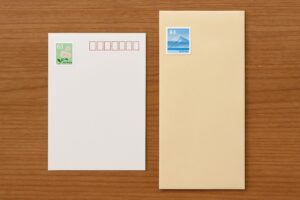 左に63円切手付きのはがき、右に84円切手付きの封筒が並べられている様子