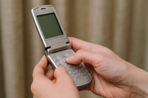 折りたたみ式の携帯電話を両手で操作している様子